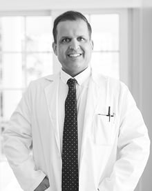 Middle age man wearing white medical coat and smiling BW